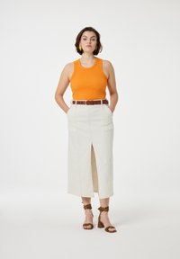 Orange ribbed tank top, high-waisted cream skirt with front slit, brown belt, and leopard print ankle strap heels.