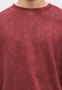 Μακρυμάνικο κόκκινο φούτερ από μαλακό βαμβάκι. Διαθέτει λαιμόκοψη τύπου crew και υφή με ελαφρώς ξεθωριασμένη εμφάνιση.