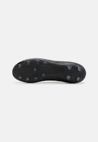 Semelle de chaussure de soccer noire avec des crampons ronds et une texture lisse. Présente un logo Nike discret et un motif sur le côté.