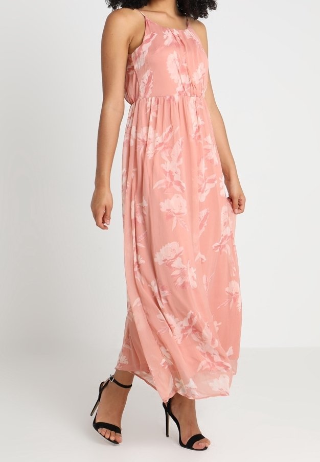 Blommig maxiklänning i mjuk rosa tyg, med tunna axelremmar, samlad midja och en flödande silhuett. Svarta ankelsandaler med remmar fulländar looken.