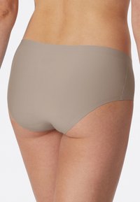 Beige højtaljede trusser lavet af glat stof med sømløse kanter, med et enkelt design uden synlige mønstre eller hardware.