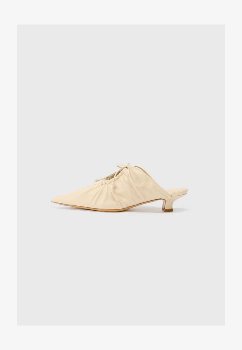 Chaussure en cuir couleur crème à enfiler avec un bout pointu, des détails froncés à l'avant et un petit talon carré.