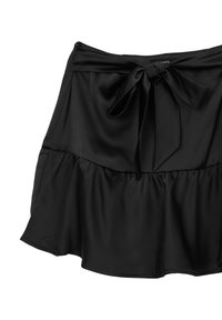 Jupe noire en tissu léger, avec un ourlet volanté, une taille élastique et un détail de nœud noué à l'avant.
