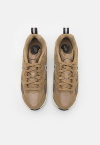 Ruskeat urheilukengät, joissa on verkko- ja synteettisiä materiaaleja. Ominaisuuksiin kuuluu pyöreät nauhat, pehmustettu nilkkaosa, sekä kontrastiväri valkoisia ja mustia yksityiskohtia.