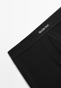 Black cotton boxer shorts featuring a soft, elastic waistband with "Massimo Dutti" logo. Smooth texture and fitted design visible.
