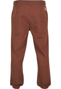 Brune joggebukser med ribbet midje og mansjetter, med sidelommer og en liten logoetikett på baksiden. Glatt bomullsblanding.