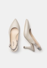 Scarpe con tacchi alti in pelle beige con punta affusolata, caratterizzate da un design con aperture e una fascia decorativa alla caviglia con dettaglio a nodo.