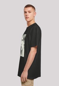 Sort bomulds T-shirt med grafisk print af et ansigt. Korte ærmer og rund hals skaber en afslappet pasform.