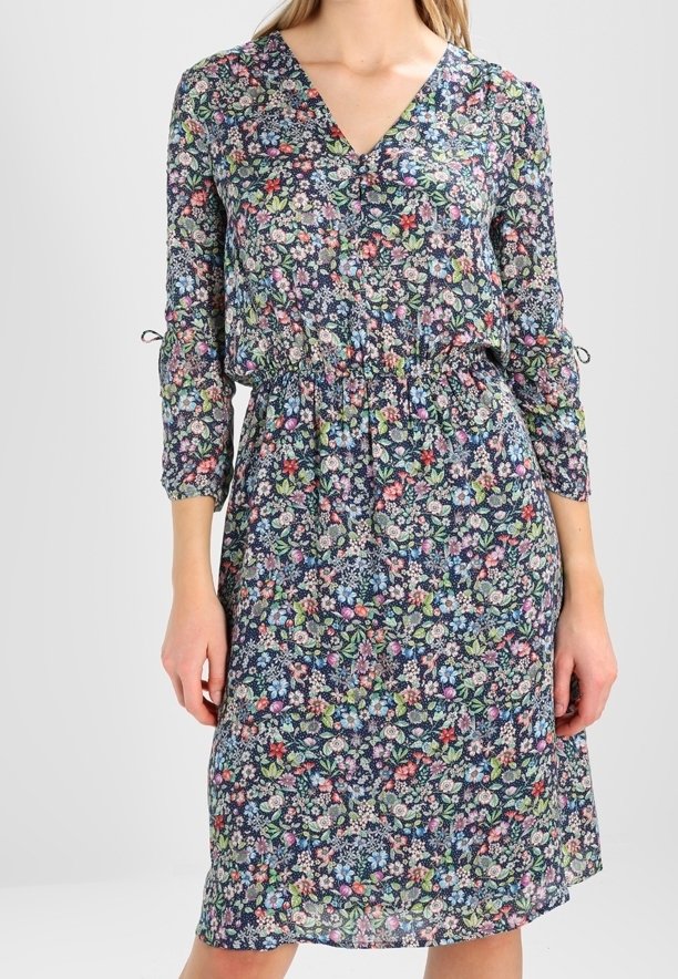 Kukkamekko syvällä V-pääntiellä, kootulla vyötäröllä ja kolmen neljänneksen hihoilla. Taustalla tummansininen väri, jossa on värikkäitä kukkakuoseja.