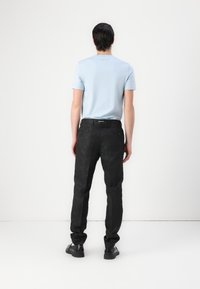 Light blue short-sleeve shirt with a regular fit, paired with black pants featuring a textured pattern and a fitted design. Black shoes complete the look.