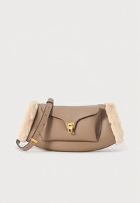 Beige skinnhåndveske med myk kremfarget kant, magnetlås og justerbar rem. Slett, rund form med teksturert finish.