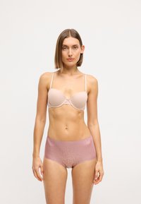 Beige polstret bh med tynde stropper, parret med lys rosa højhalsede trusser med et subtilt tekstureret mønster.