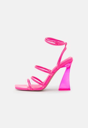 Sandale à talon haut rose avec trois brides transparentes, un bout carré et un talon bloc translucide épais. Fini lisse et brillant.