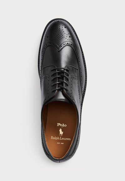 Pantofii de birou din piele neagră, cu perforații tip brogue și bot tip wingtip, având logo-ul Polo Ralph Lauren pe interiorul bradului de tan.