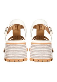 Paire de sandales blanches à bout ouvert avec talons blocs et brides à la cheville, vue de dos sur fond blanc.