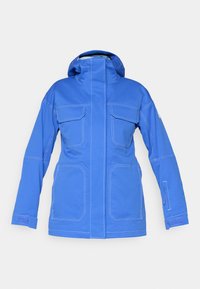 Μπλε αδιάβροχο μπουφάν με ψηλό γιακά, δύο μεγάλες μπροστινές τσέπες και μία κλειστή τσέπη στο μανίκι. Διαθέτει αντίθετη λευκή ραφή.