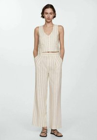Beige en witte gestreepte twee-delige outfit met een cropped mouwloos topje met knopen en wijde broek, gemaakt van lichtgewicht stof.