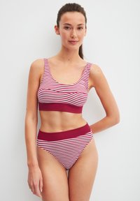 Twee-delig badpak met rode en witte horizontale strepen. De top heeft een ronde hals en dikke bandjes; de broek heeft een hoge taille.