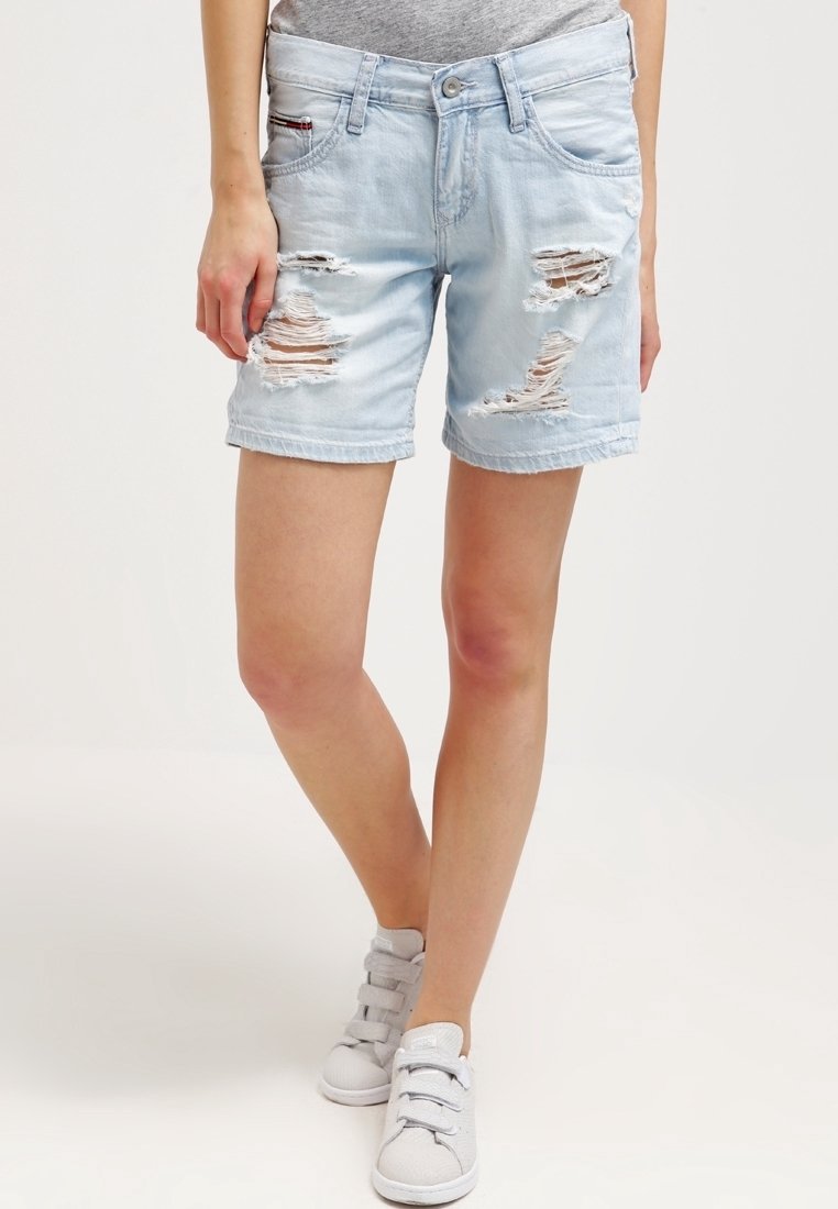 Ljust blå denimshorts med slitningar, mitt på låret längd, femficksdesign och uppvikta benslut. Bärs med grå sneakers.