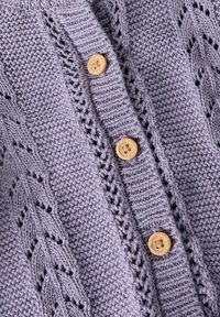 Strikket cardigan i lys lavendel med vertikale riller, utsmykket med dekorative blondefronter og naturlige treknapper.