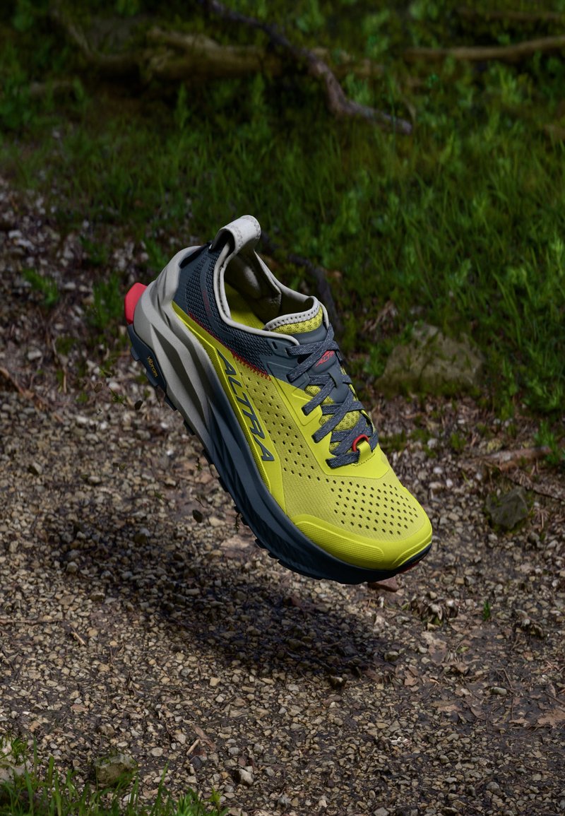 Chaussure de trail running avec un dessus en maille jaune, des accents gris, un talon rouge et une semelle texturée. Comprend des perforations pour la respirabilité et des détails réfléchissants.