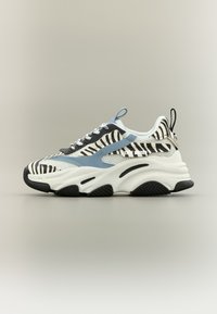 Baskets blanches avec accents noirs et imprimé zèbre, détails bleu clair, semelle épaisse blanche et motif de crampons prononcé. Dotées d'un design à lacets.