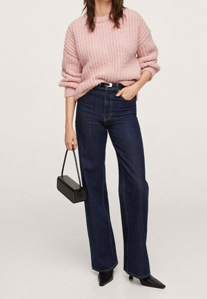 Jasnoróżowy prążkowany sweter, ciemnoniebieskie szerokie spodnie z wysokim stanem, czarne szpilki z ostrym noskiem oraz mała czarna torebka o fakturze.