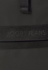 Borsa in tessuto nera con manico piatto e logo impresso "JOOP! JEANS". Superficie opaca con una texture liscia. Progettata per la versatilità.