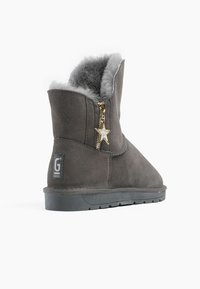 Botín de ante gris con forro de piel gris, cremallera lateral con un charm de estrella dorada y suela de goma negra.