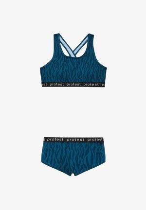 Completo sportivo blu composto da reggiseno e pantaloni corti con motivo a strisce di tigre in blu scuro. Presenta una cintura elastica nera con la scritta "protesta" ripetuta.