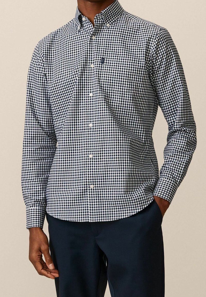 Camicia a maniche lunghe a scacchi blu navy e bianca con colletto a bottoni e taschino sul petto, realizzata in tessuto di cotone intrecciato.