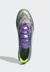 Paarse en groene voetbalschoenen met een gestructureerde bovenkant, met een gestroomlijnd ontwerp, centrale vetersluiting en een heldere neonaccent op de zool.