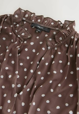 Brun bluse med prikker, flæsekant ved halsen og korte ærmer. Fremstillet i et glat, letvægtsstof med et mærke mærket "NEXT".