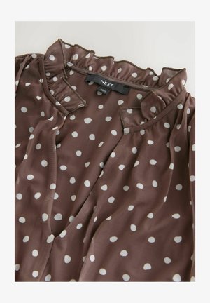 Brun bluse med prikker, flæsekant ved halsen og korte ærmer. Fremstillet i et glat, letvægtsstof med et mærke mærket "NEXT".