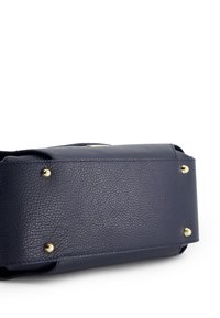 Marineblaue Lederhandtasche mit strukturierter Oberfläche, goldfarbenen Hardware-Details, rechteckiger Form und vier Metallfüßen an der Unterseite für Stabilität.