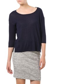Marineblauer locker gestrickter Pullover mit weitem Ausschnitt und Dreiviertelärmeln, kombiniert mit einem hellgrauen melierten Rock.