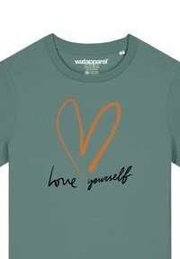 T-shirt vert à manches courtes avec un col rond. Présente un graphisme de cœur orange et le texte "aime-toi" en cursive noire.