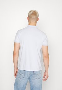 Světle modrá polo tričko s límečkem, krátkými rukávy a rovného spodním lemem. Měkká bavlněná tkanina, minimální značení a přiléhavý střih.