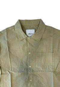 Maglietta beige con bottoni, colletto classico, piccola tasca frontale, texture morbida, con etichetta bianca con logo "GAS" all'interno del colletto.