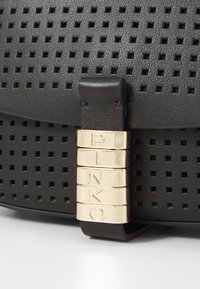 Borsa in pelle nera forata con una superficie liscia e ritagli quadrati; presenta un accessorio in metallo dorato con "PINKO" inciso sulla chiusura.
