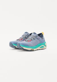 Scarpe da esterno di colore azzurro chiaro in suede testurizzato, con intersuola teal a contrasto e dettagli multicolori. Presentano una suola in gomma resistente per una maggiore trazione.