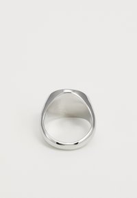 Anello in metallo argentato con un design liscio e arrotondato; banda larga e finitura lucida; l'interno presenta una superficie leggermente texture.