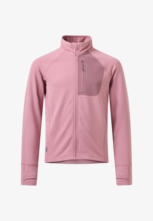 Jeune personne portant une veste rose ajustée zippée avec une poche sur la poitrine et un legging noir, se tenant avec une main sur la hanche devant un fond uni.