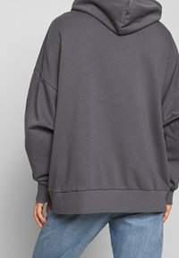 Sudadera gris en talla grande, hecha de una suave mezcla de algodón. Cuenta con capucha, puños acanalados y un corte holgado para mayor comodidad.