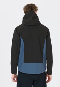 Schwarz-blaue Softshell-Jacke mit Kapuze, tailliertem Design, glatter Textur und kontrastierenden Farbpanelen an den Seiten und am Rücken.
