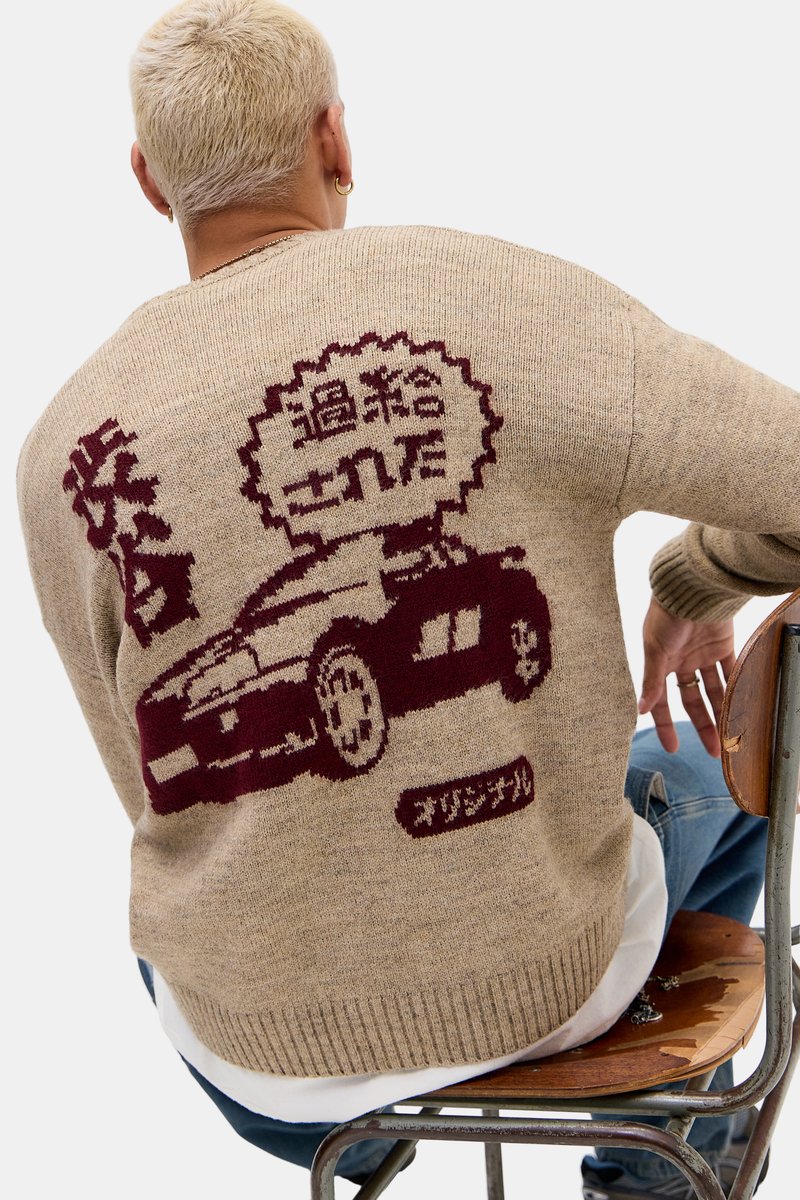 Strikkegenser i beige med burgunder bilgrafikk og japansk tekst på ryggen. Har ribbet kant og mansjetter, avslappet passform.