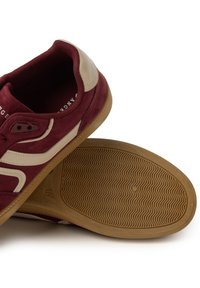 Zapatillas de ante burdeos y cuero beige con suela de goma, que cuentan con un diseño clásico y una suela con dibujo.