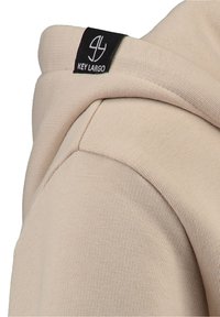 Felpa con cappuccio beige con texture a costine, caratterizzata da un'etichetta nera sul collo che mostra il logo "KEY LARGO".