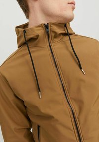 Veste zippée marron avec capuche, fabriquée en tissu lisse, dotée de cordons de serrage noirs et d'accents argentés sur la fermeture éclair.