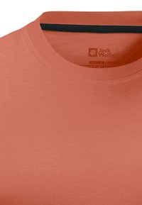 Koraalkleurig T-shirt met korte mouwen van zachte stof, met een ronde hals en een contrasterende donkere streep aan de binnenkant van de kraag.
